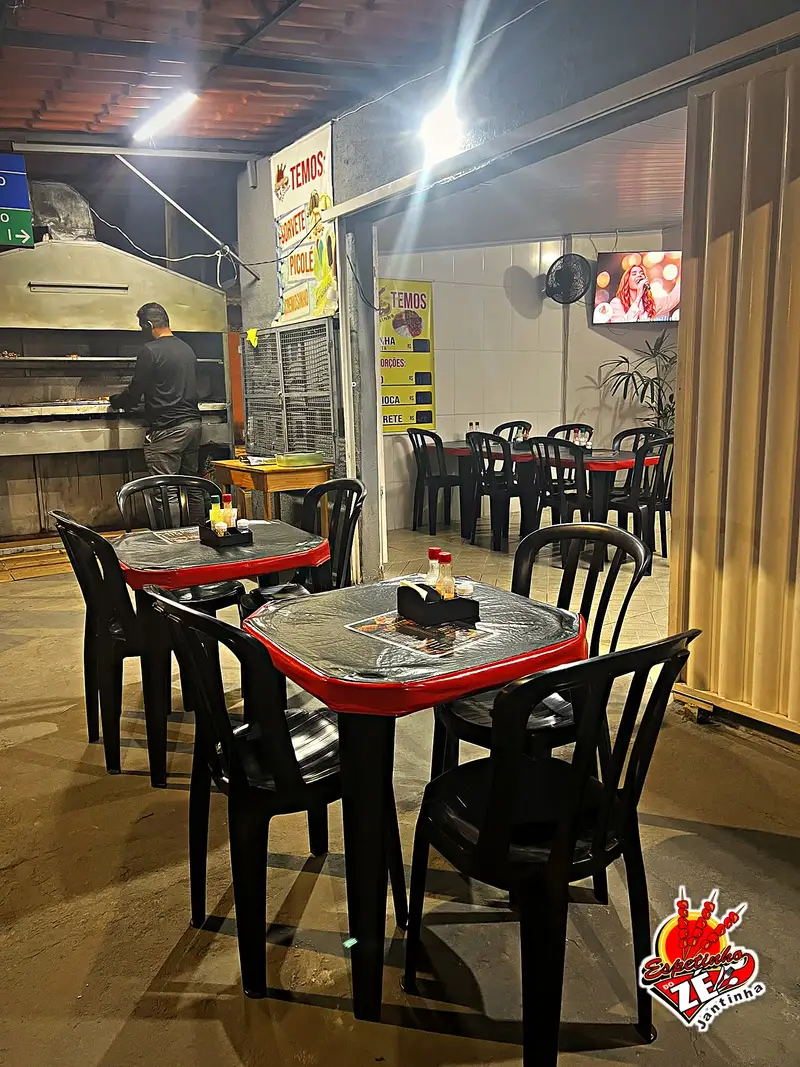 Salão com mesas do Espetinhos do Zé, com a churrasqueira ao fundo